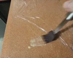 Step <p>Recortar tantos cuadrados de papel film como rebanadas hayamos hecho. </p><p>Extender en una mesa y pincelar con mantequilla derretida.</p> illustration